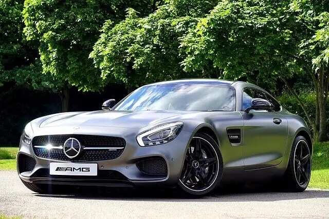 Серый матовый спортивный автомобиль Mercedes-AMG GT S Coupe, припаркованный на фоне деревьев, символизирующий качество и техническое превосходство.
